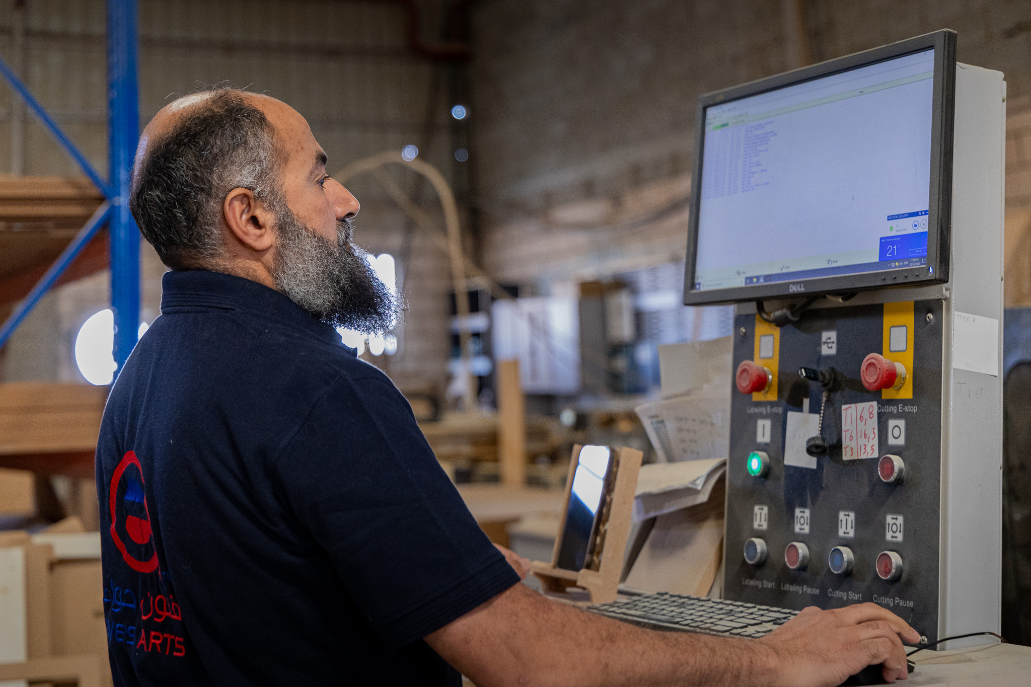 فني فنون حواء أثناء متابعة شاشة تشغيل ماكينة CNC داخل المصنع